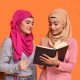two women in hijabs are reading a book